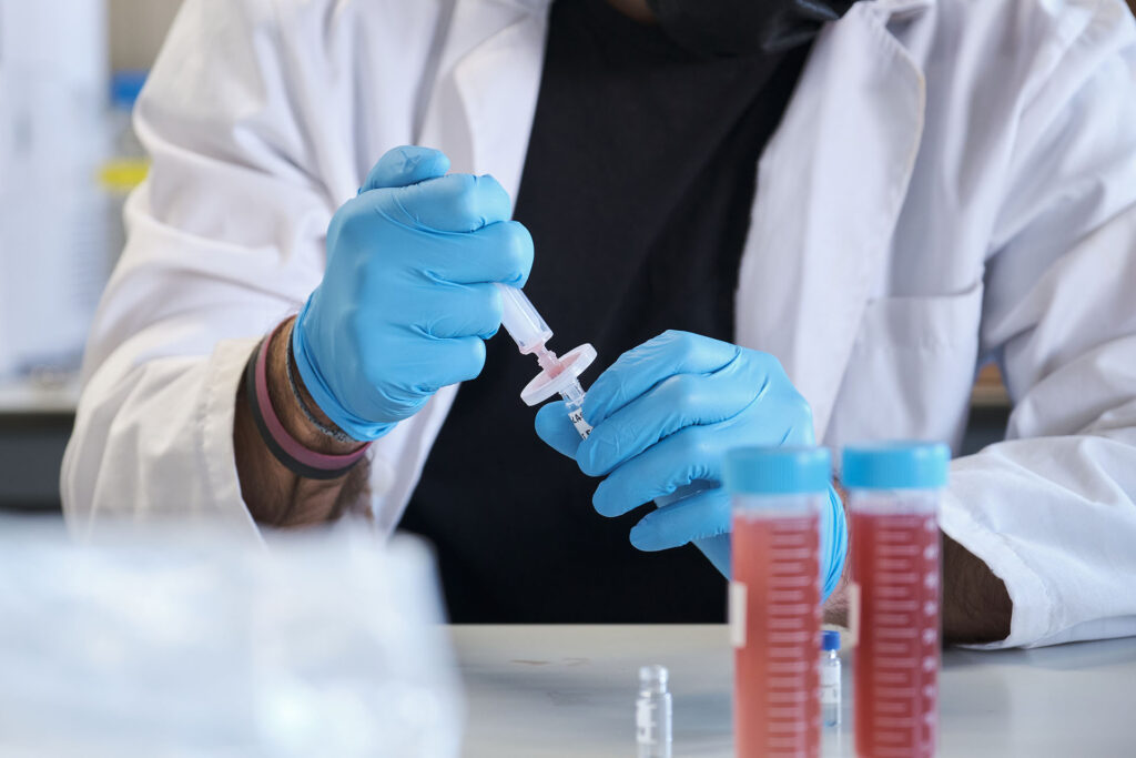 Scientist in white lab coat filter sample into HPLC vial.